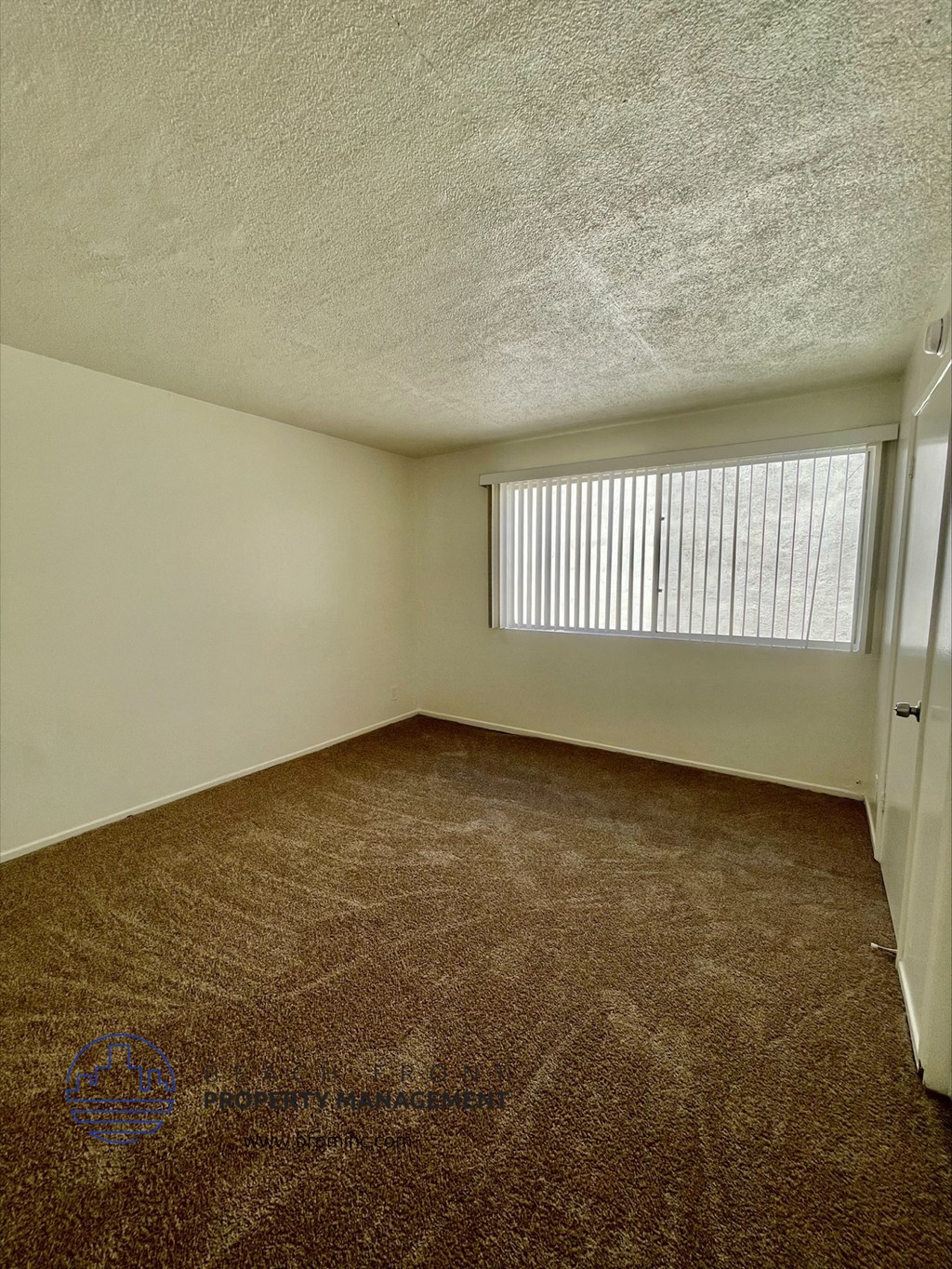 the spacious living room of an apartment with a window